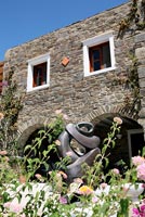 Traditional stone house and modern garden sculpture