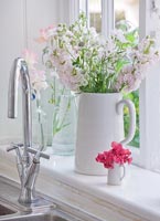 Sweet peas and Delphinium flowers in white jugs