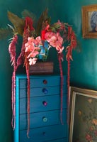 Turquoise cabinet with faux flowers in majolica pot