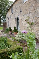 Stone house and garden borders with Poppies and Valerians