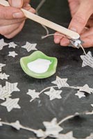 Creating a simple Christmas decoration using newspaper and string - adding glue to star