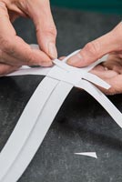 Using paper strips to create star shaped decorations -  threading strip beneath folded section