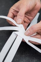 Using paper strips to create star shaped decorations - folding each strip in half