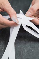 Using paper strips to create star shaped decorations - pulling strip through to create a pointed triangular corner