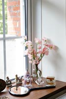 Vase of Sweet peas and cosmetics on windowsill