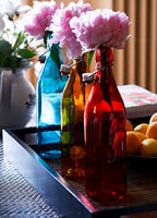 Peony flowers in colourful bottles