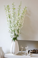 White Larkspur flowers in vase by limestone fireplace