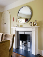 Round mirror above fireplace