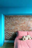Exposed brick wall behind bed