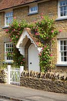 Cottage front door with Roses growing around porch