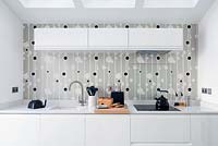 White kitchen units and patterned wallpaper