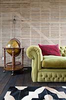 Chestefield sofa and globe drinks cabinet against exposed lath and plaster wall