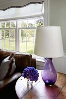 Purple pansy flowers and lamp on wooden side table