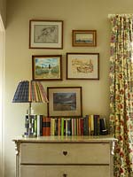 Framed paintings above vintage chest of drawers