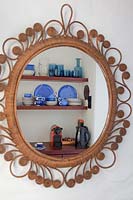 Blue crockery reflected in cane mirror
