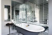 Roll top bath surrounded by mirrored tiles