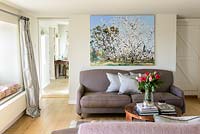 Landscape painting above brown sofa