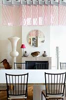 Modern dining room with pink suspended light by Johanna Grawunder