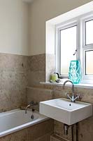 Modern bathroom sink with limestone splashback