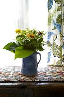 Colourful flowers and foliage in blue jug