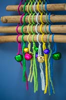 A colourful christmas tree made with sticks coloured wool and miniature baubles against a blue backdrop