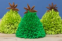 Miniature Christmas trees made from wool pompoms and star anise pods
