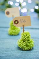 Miniature Christmas trees made from wool pompoms with place setting name cards 