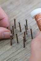 Making copper wire star decorations - Weave the copper wire around the nails to form a star 