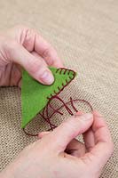 Making stitched felt christmas decorations - Sew two felt triangles together, leaving a gap at the base for inserting the stuffing 