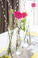 Arrangements of Pussy Willow stems, Gerbera and Freesia flowers on dining table
