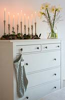 Christmas decorations and vase of Amaryllis flowers on chest of drawers