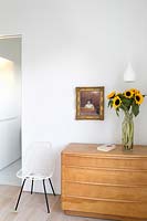 Vase of Sunflowers on wooden chest of drawers