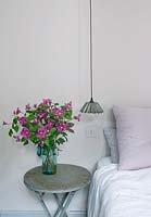 Bedside table with vase of Clematis flowers