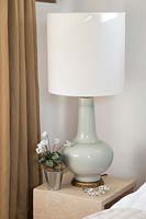 Modern lamp and potted Cyclamen on bedside table