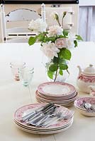 Classic tableware and vase of Roses on kitchen table