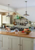 Kitchen island with wooden worktop and brushed steel pendant lights