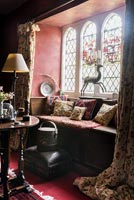 Window seat with cushions showing antique stump work and stained glass window - Cothay Manor