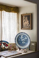 Landing windowsill with fragment of stained glass, Arts and Crafts tile and Delft plate 
