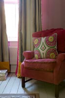 Patterned cushion on pink armchair