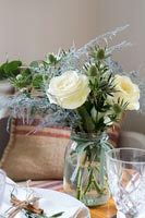 Roses and Sea holly flowers in glass jar