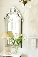 Vase of Lilies in front of venetian style mirror