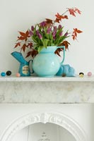 Jug of Tulip flowers and Maple foliage on mantlepiece