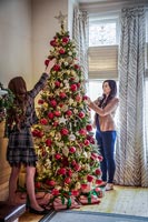 Woman and daughter decorating christmas tree