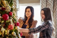 Woman and daughter decorating christmas tree