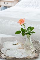 Detail of single rose in a glass vase in classic country bedroom