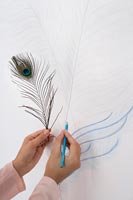 Detail of hands drawing a peacock feather