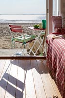 View out of beach hut to chair and table