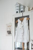 White dress hanging on wooden dresser