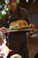 Man carrying tray of slow baked salt dough wrapped shoulder Perthshire lamb with rosemary
