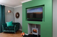 Modern living area with green chimney breast and wood burner